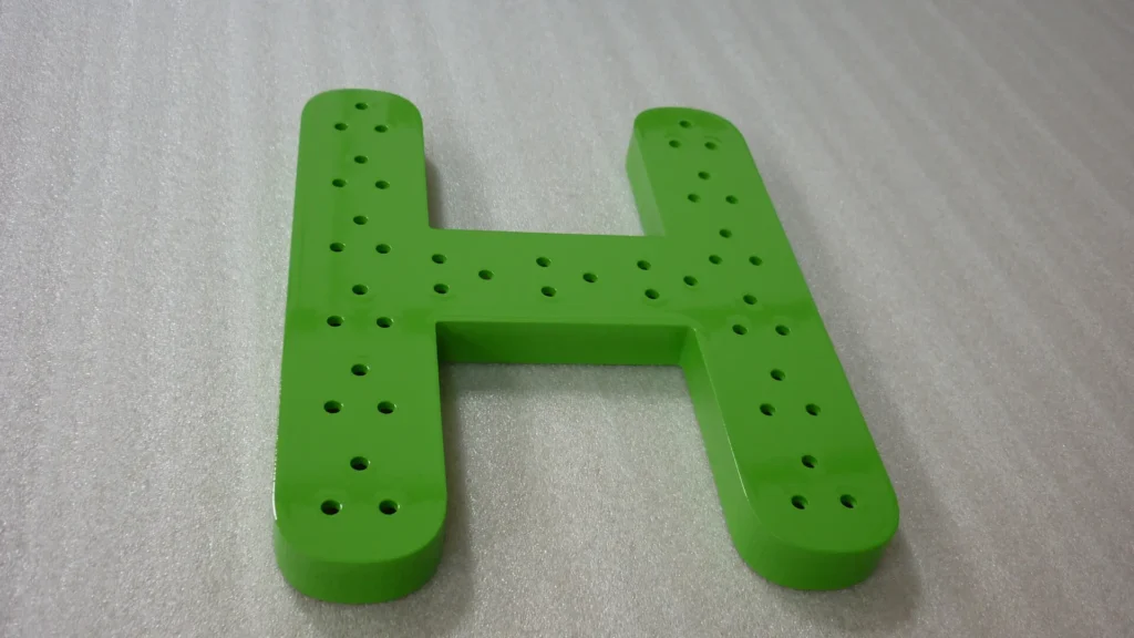 lettre "H" perforée pour insérer diodes en komacel laqué coloris vert
